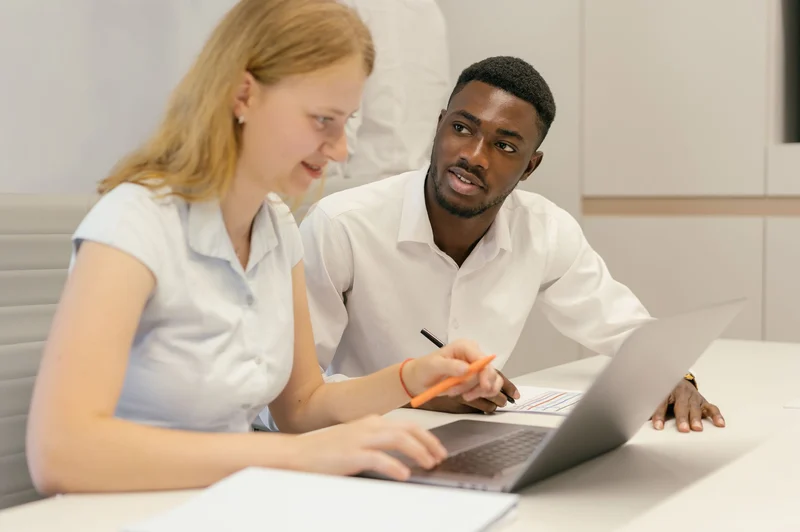 Two colleagues reviewing a process together at a laptop
